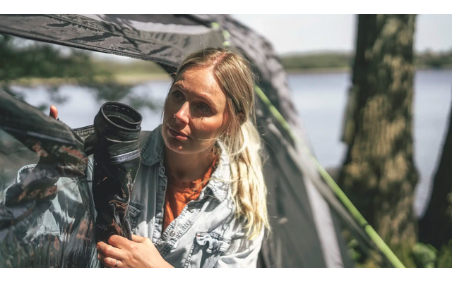 Frau mit langem blondem Haar hält und umarmt ein schwarzes Haustier im Freien