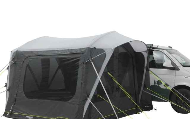 Weißes Wohnmobil mit angehängtem grauen Vorderzelt auf einem gepflasterten Platz