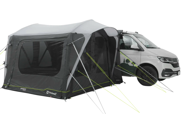 Weißes Wohnmobil mit angehängtem grauen Vorderzelt auf einem gepflasterten Platz