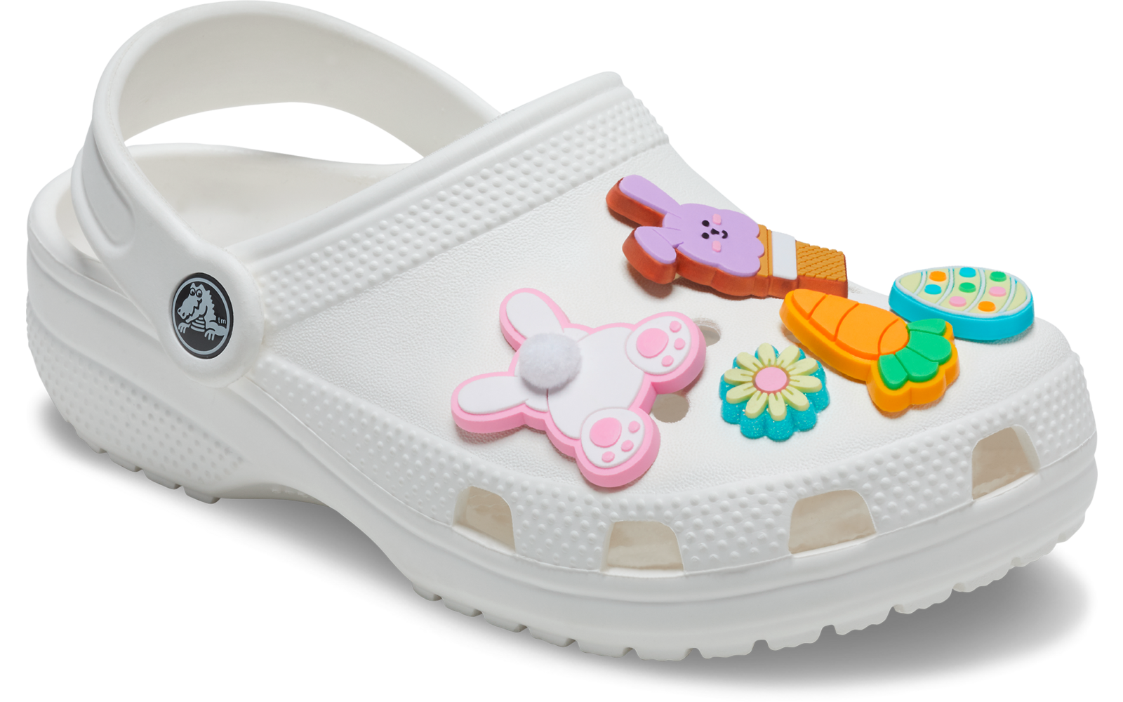 Zueco blanco con orificios de ventilación y correa trasera, decorado con dijes coloridos (conejo rosa, zanahoria naranja, dos flores, dije redondo multicolor)