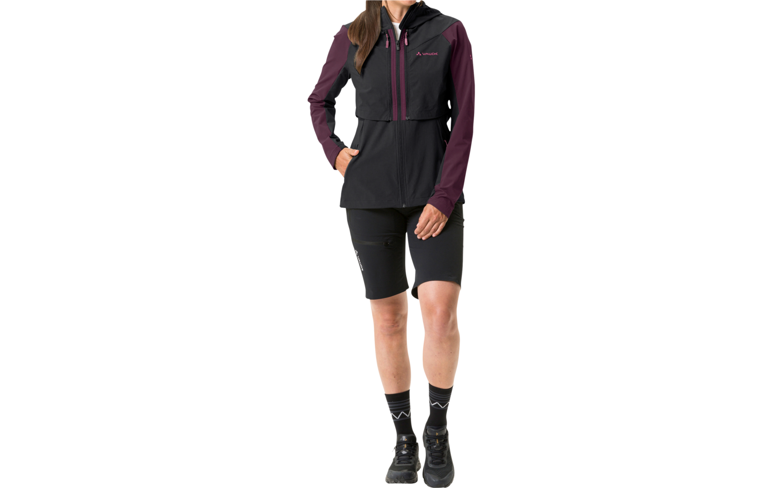 Frau trägt schwarze Weste, lila langärmliges Shirt, schwarze Shorts und schwarze Stiefel