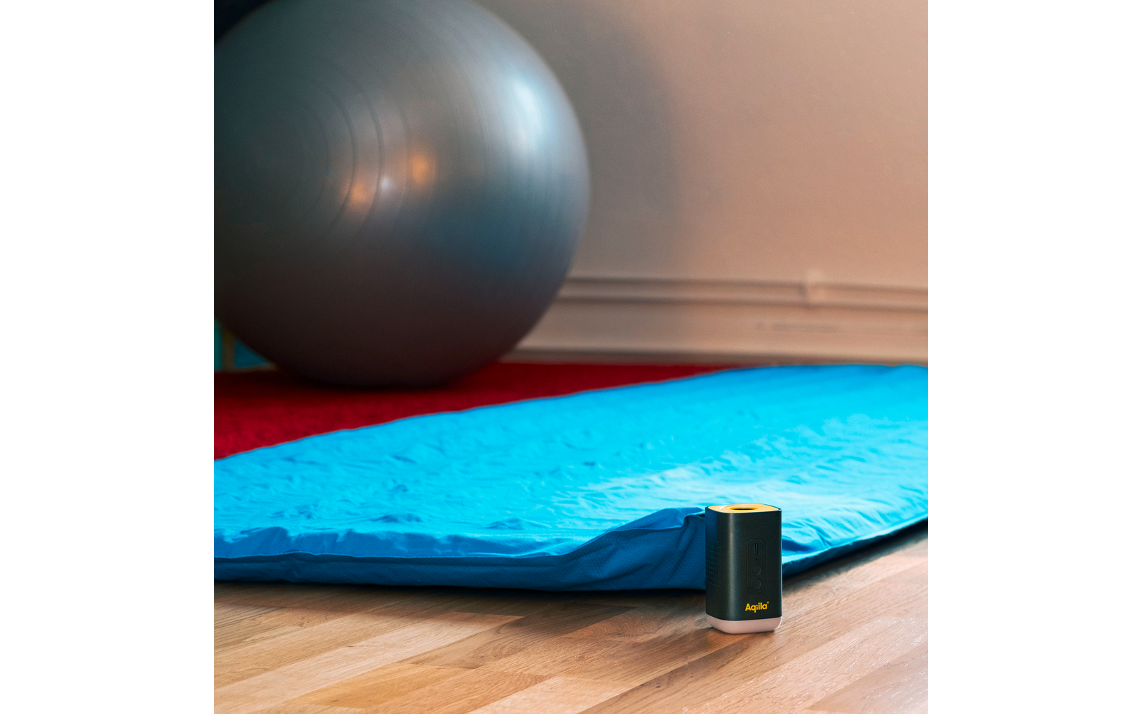 Blauwe yogamat en grijze fitnessbal voor witte muur
