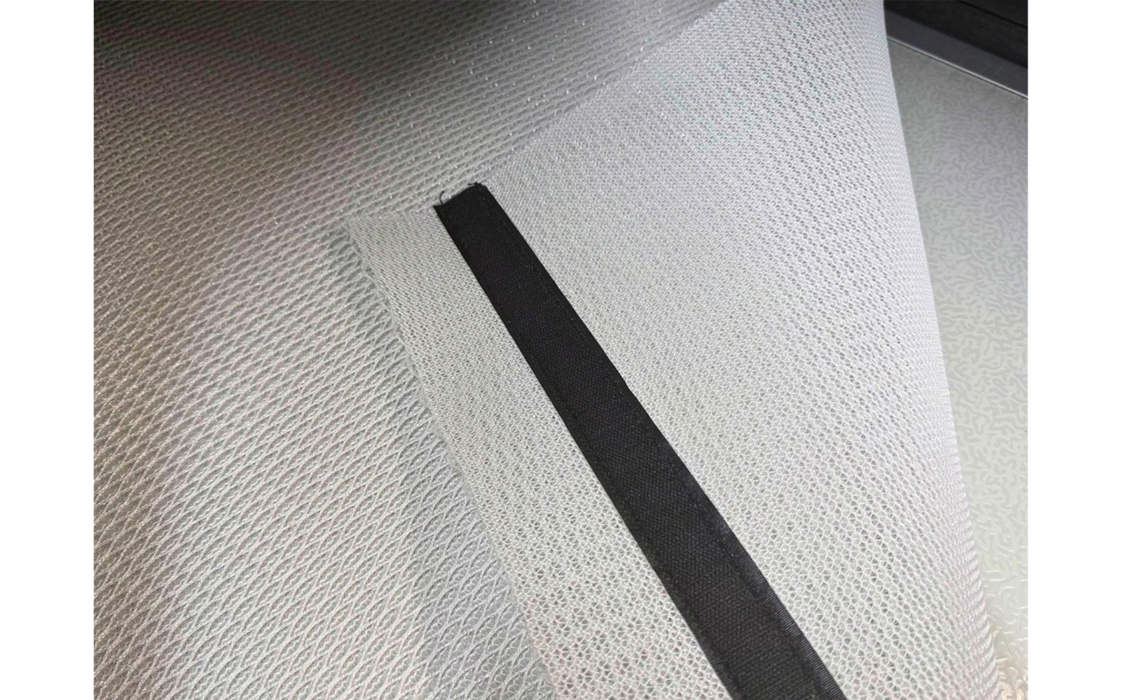 Gray-white fine mesh fabric layers overlapping, with a black fabric strip