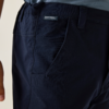 Close-up of a person's hip wearing dark blue trousers with a visible label and a partially visible left hand