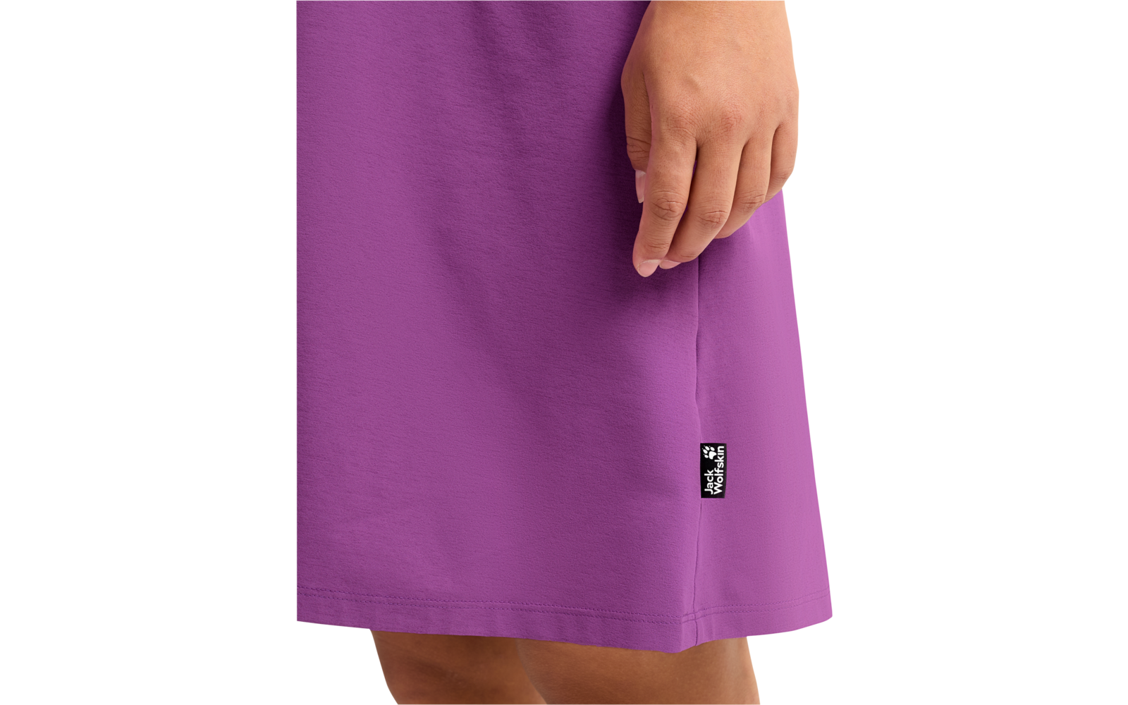 Unterkörper einer Person in einem violetten Kleid, rechte Hand an der Seite, sichtbare Oberschenkel, kleines schwarzes Etikett am Saum