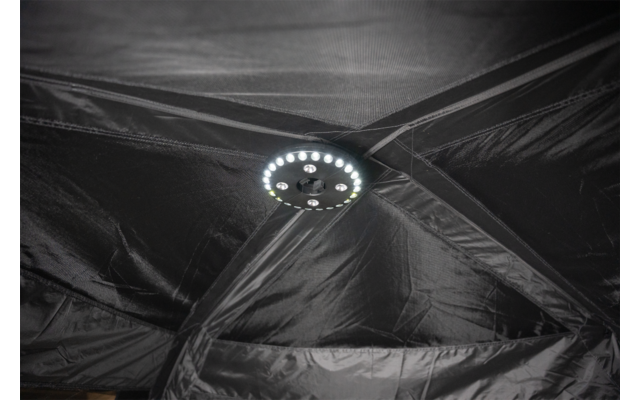 Schwarze Stoffbahnen mit Nähten und sich kreuzenden Verstärkungen, in der Mitte eine runde LED‑Leuchte mit einem Ring heller LEDs