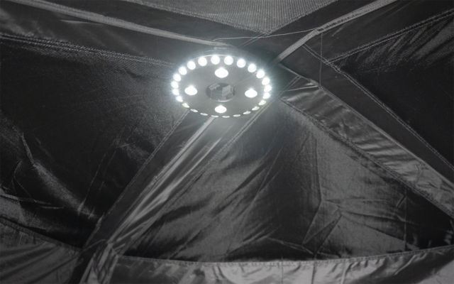 Kreisförmiger LED-Leuchtring in der Bildmitte, umgeben von schwarzen Stoffpaneelen mit sichtbaren Nähten