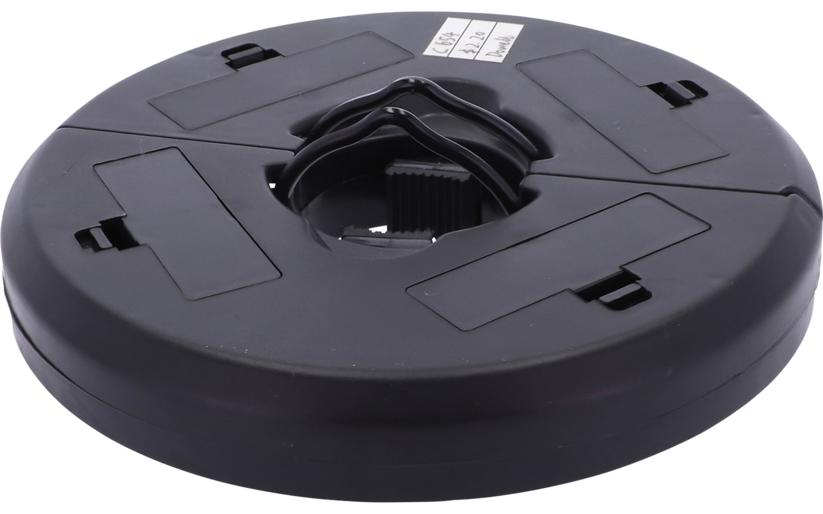 Runde schwarze Kunststoffscheibe mit zentraler runder Öffnung, sichtbarem inneren Zahnkranz, vier rechteckigen Aussparungen und kleinem weißen Etikett oben