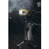 Nahaufnahme eines Fahrradlenkers mit eingeschalteter Lampe und Wassertröpfchen in der Luft