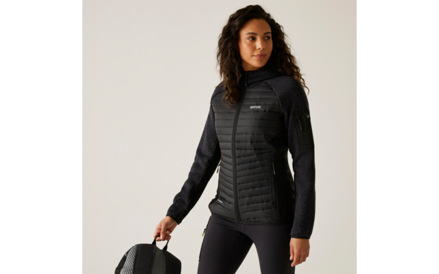 Femme aux cheveux bouclés portant une veste noire tenant une poignée de valise