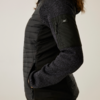 Personne de profil portant un pull noir et un gilet noir, bras plié