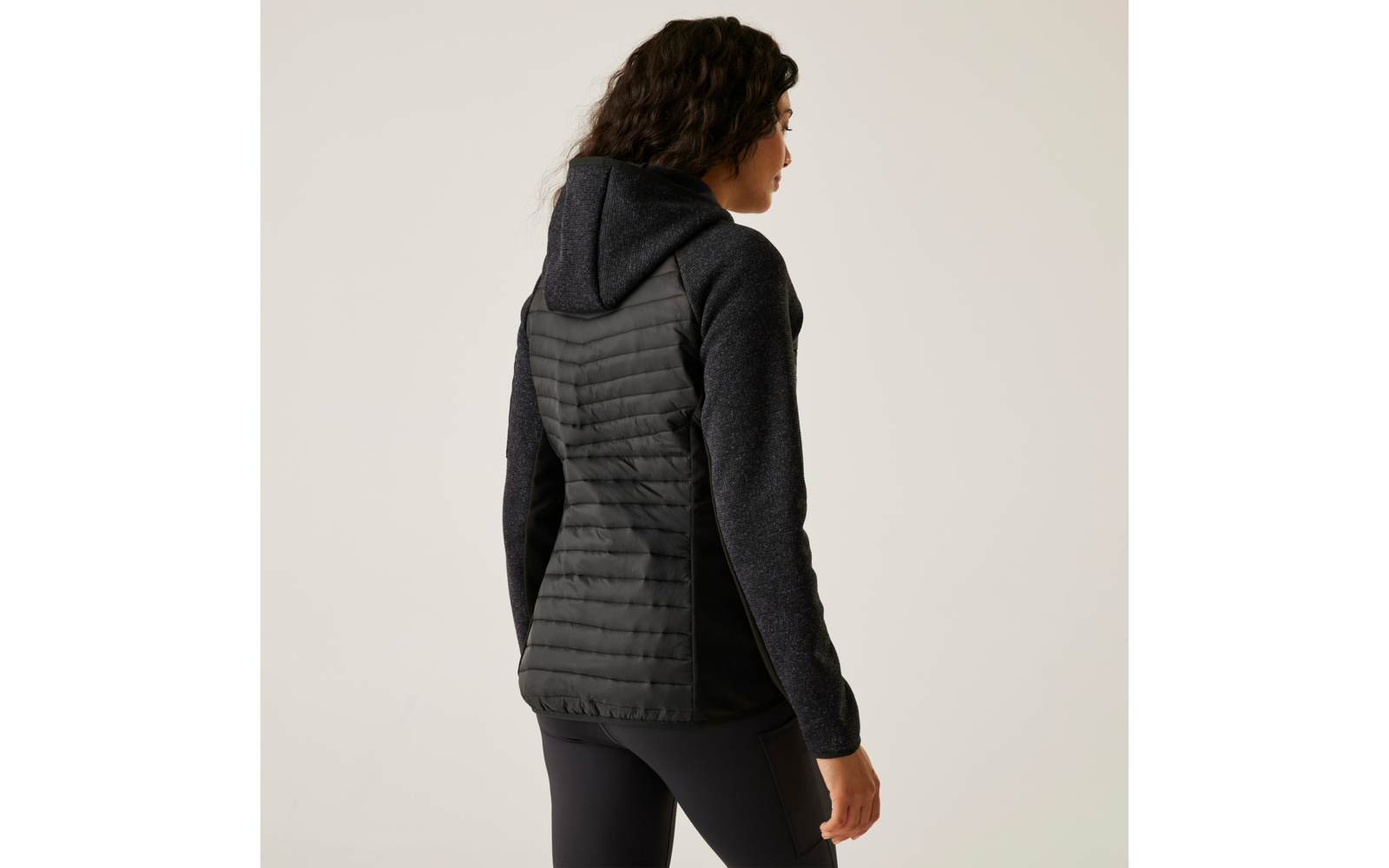 Femme vue de dos portant une veste matelassée noire avec capuche