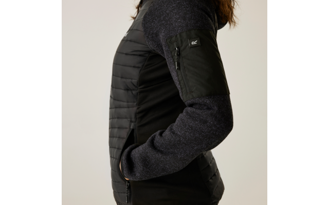 Personne de profil portant un pull noir et un gilet noir, bras plié