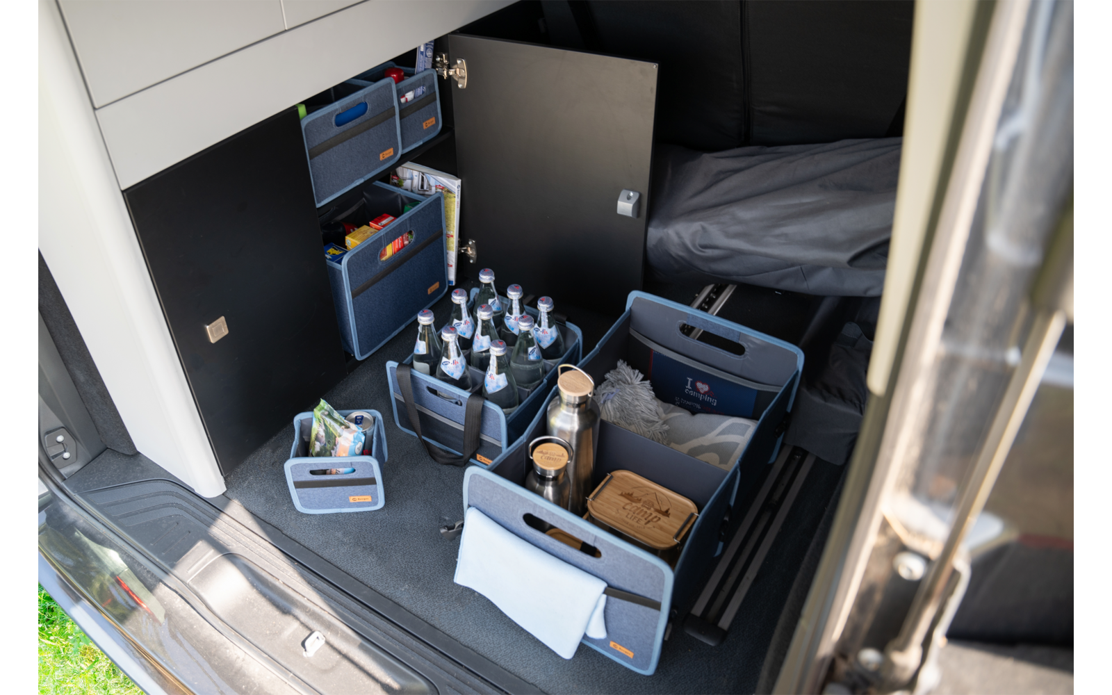 Vue de l'arrière ouvert d'un véhicule avec plusieurs caisses de boissons réfrigérées et des bouteilles individuelles