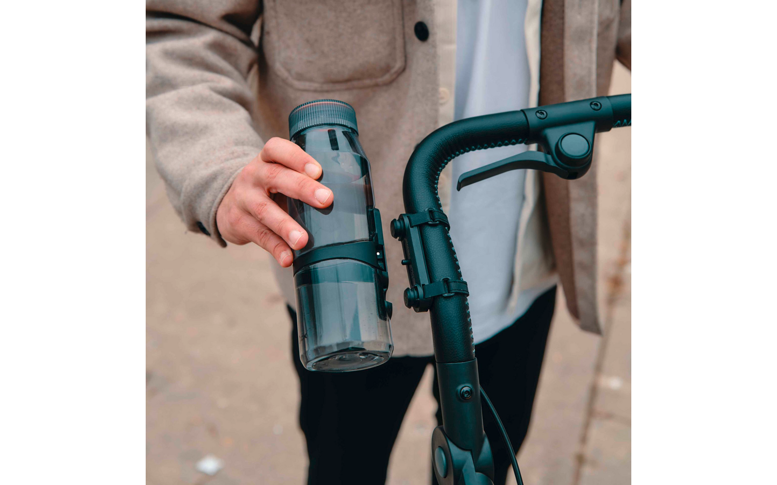 Person hält einen wiederverwendbaren Trinkbecher am Griff eines Rollators