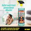 Frau mit Handtuch im Nacken neben einem Stapel gefalteter Handtücher und einer Sprühflasche Reinigungsmittel