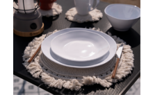 Assiette blanche sur une table avec un dessous de plat gris, à côté une tasse blanche et des couverts