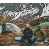 Drei Personen beim Camping in den Bergen mit Schnee im Hintergrund