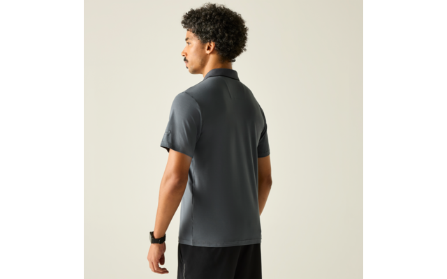 Mann steht mit dem Rücken zur Kamera, trägt dunkelgraues Poloshirt und schwarze Shorts, Smartwatch am linken Handgelenk, heller Hintergrund