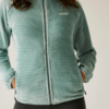 Person trägt eine hellblaue Fleecejacke mit Reißverschluss und hat die Hände in den Taschen