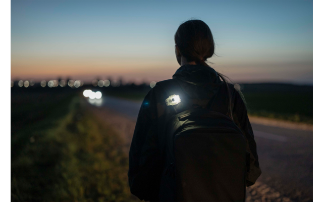Person mit Rucksack geht am Abend auf einem Weg entlang