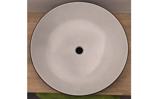 Ronde witte wastafel met zwarte rand en centrale afvoer op een houten blad