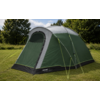Green-gray pitched tent with closed arched door, fluorescent guy lines, black hem with 'Outwell' logo, on grass with trees and a blue sky with clouds