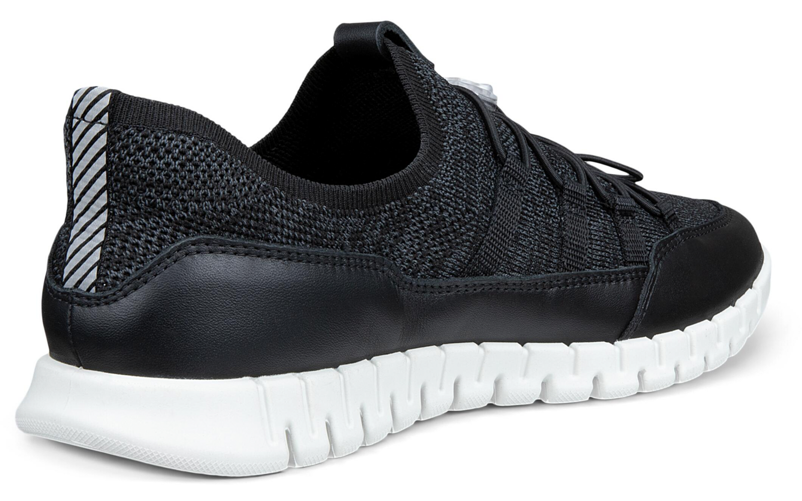 Zapatilla negra en vista lateral/trasera, empeine de punto, cordones negros, suela blanca segmentada, tirador del talón con franjas reflectantes