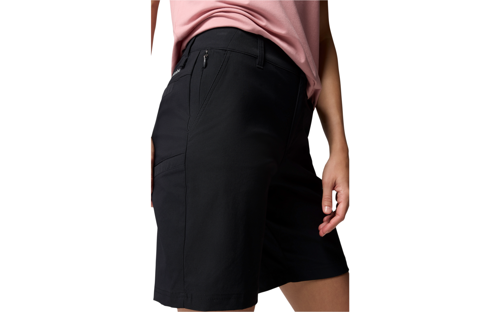 Bas du corps d'une personne portant un short bermuda noir avec poche zippée latérale et un haut rose, main droite visible sur le côté