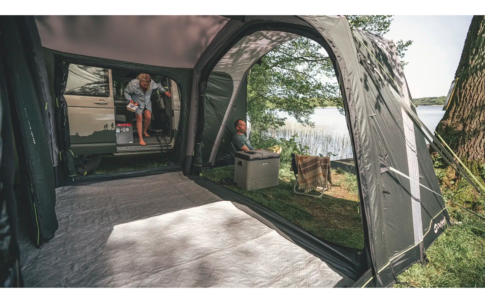 Innenansicht eines Zeltes mit offenem Eingang und Blick auf einen Garten mit Bäumen