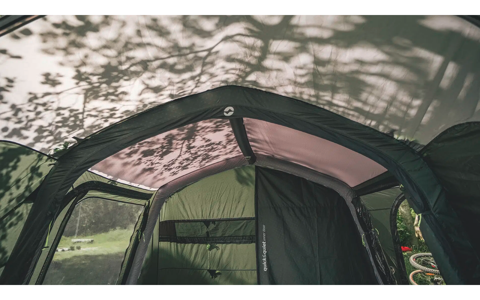 Zelt mit geöffnetem Eingang und Baumzweigen als Schatten auf dem Dach