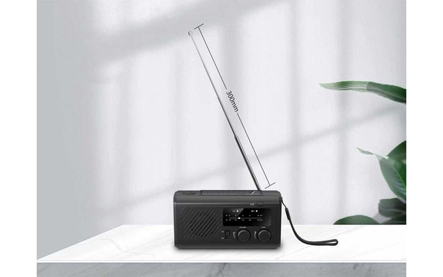 Schwarzes rechteckiges Radio mit ausgezogener Teleskopantenne und Frontknöpfen auf weißer Oberfläche; Pflanzenblatt rechts, Fenstergitter-Schatten an der Wand; Antenne mit "30cm" markiert