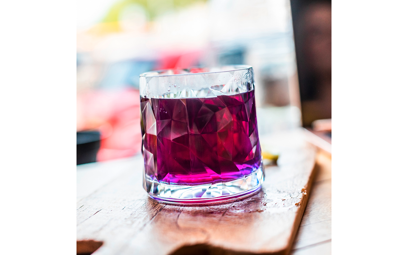 Glas mit rotem Getränk auf Holztisch
