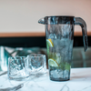 Gläser und ein Krug mit Wasser und Limettenscheiben auf einem Tisch