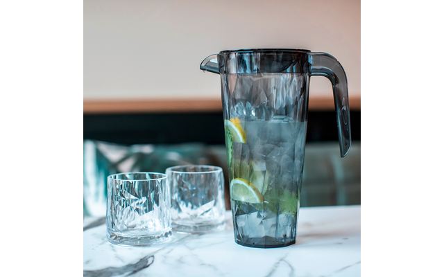 Gläser und ein Krug mit Wasser und Limettenscheiben auf einem Tisch