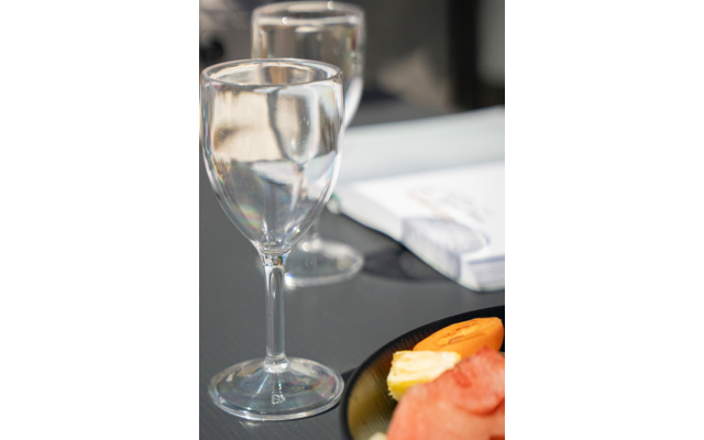 Twee glazen water, een wit tafellaken op de achtergrond en een bord met gesneden sinaasappel