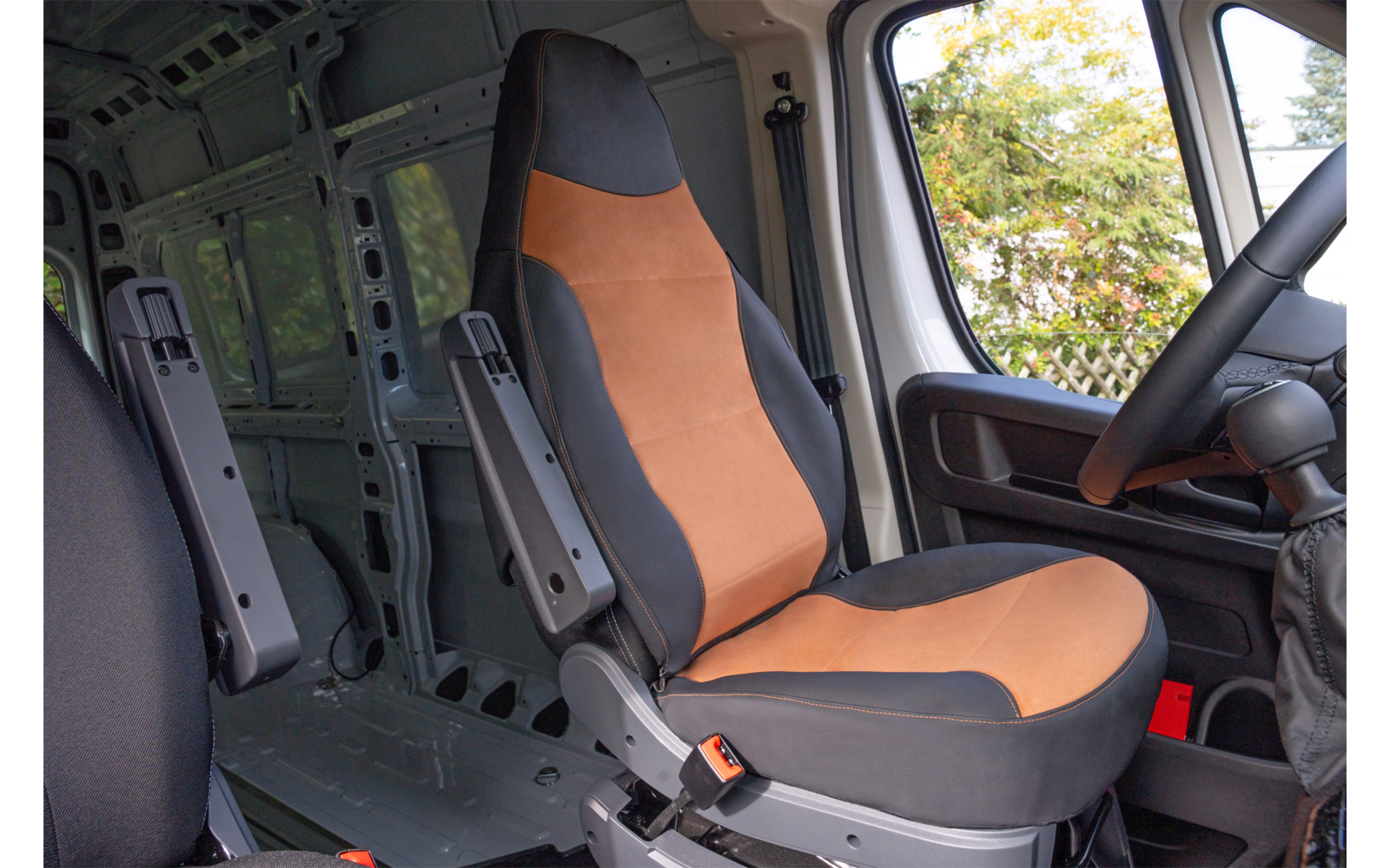 Intérieur d'une fourgonnette avec un siège orange et noir, volant, portière et espace de chargement vide