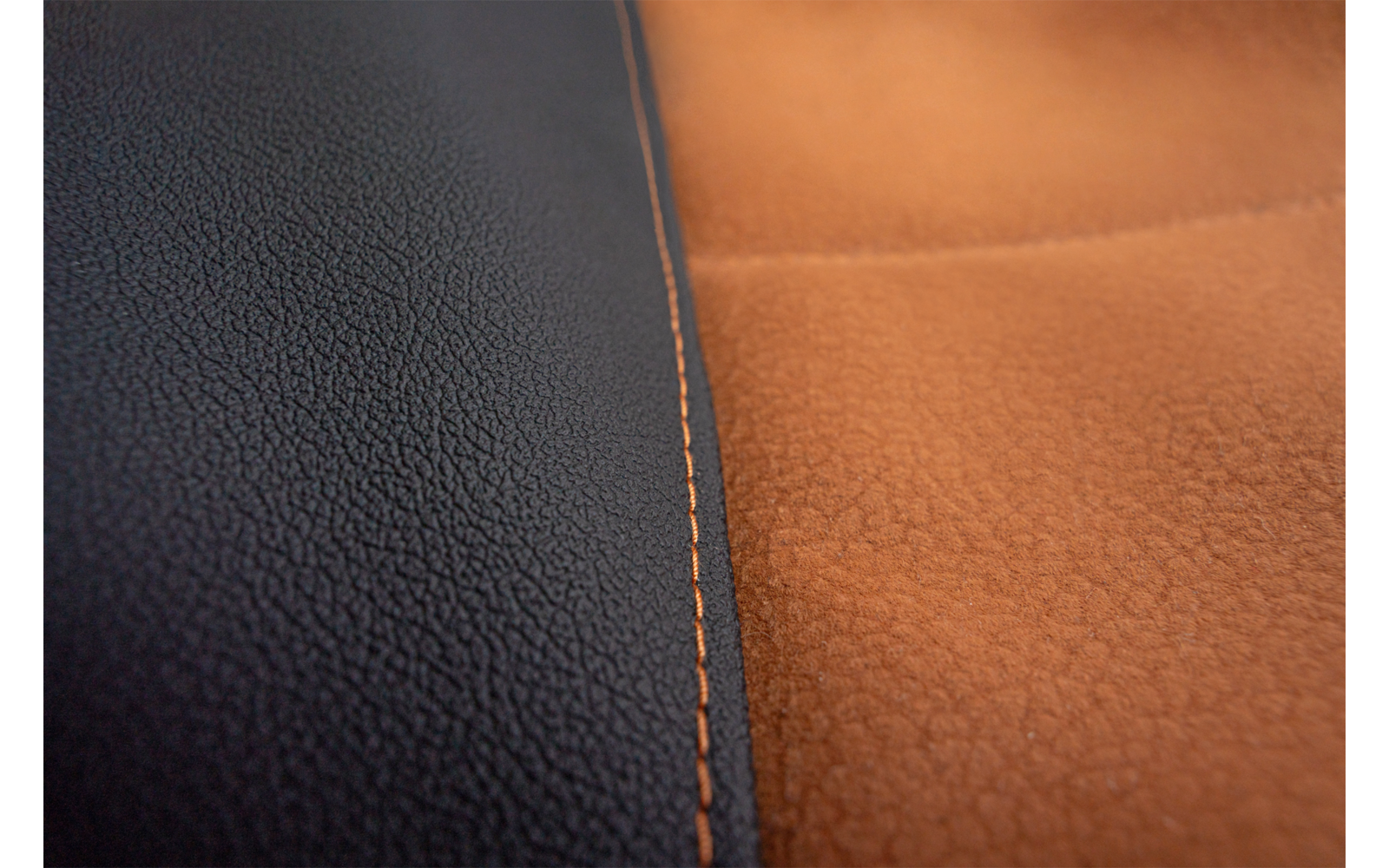 Gros plan de deux surfaces en cuir : à gauche bleu-noir, à droite brun ; couture visible avec surpiqûre contrastante