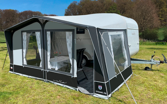 Caravan with attached awning on a grassy field under blue sky