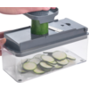 Hand gebruikt een groentesnijder met courgetteschijfjes in de bak