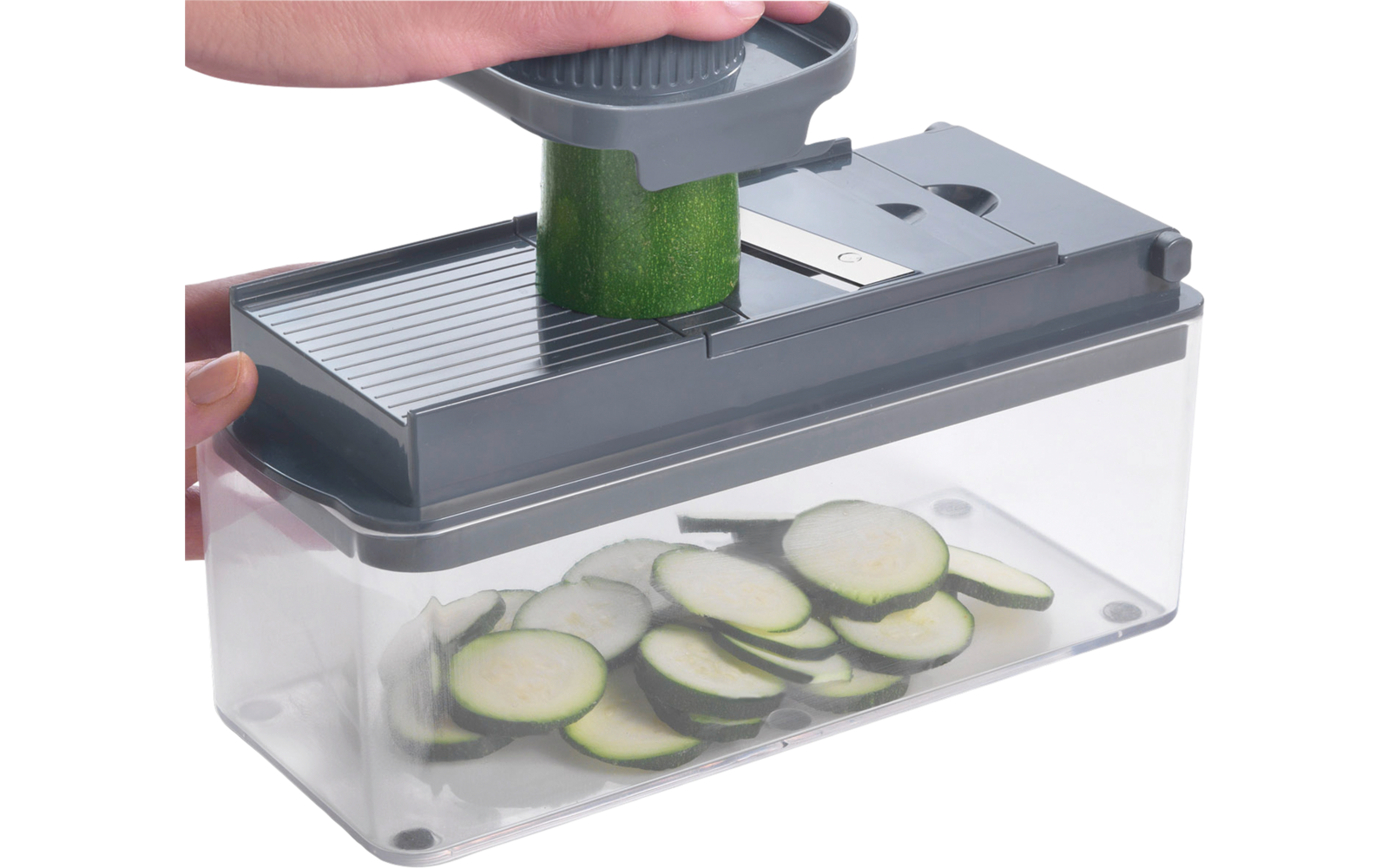 Hand gebruikt een groentesnijder met courgetteschijfjes in de bak