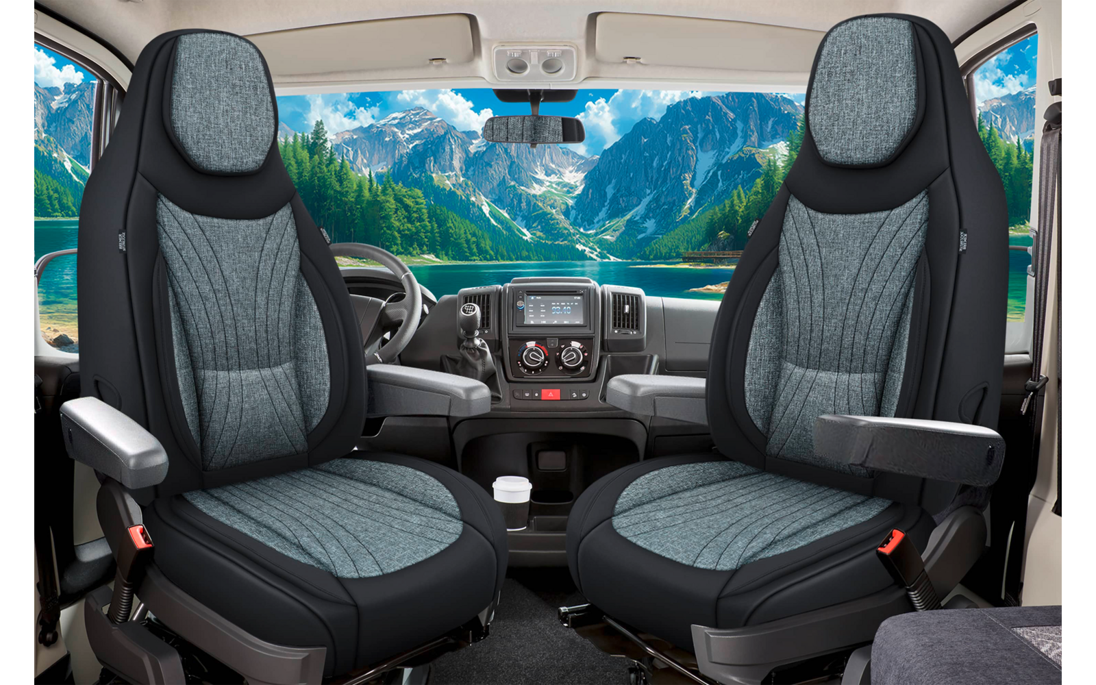 Innenraum eines Fahrzeugs mit zwei grauen Vordersitzen mit Armlehnen, Lenkrad und Armaturenbrett, durch die Windschutzscheibe ein Bergsee