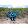 Sandiger Strand mit Gras und einem blauen Paar Schuhe, die auf dem Boden liegen