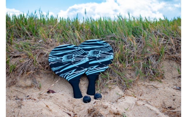 Sandiger Strand mit Gras und einem blauen Paar Schuhe, die auf dem Boden liegen