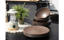 Mehrere braune Teller und Schalen auf einem schwarzen Tisch neben einer weißen Laterne und einem kleinen grünen Pflanze in einem Topf