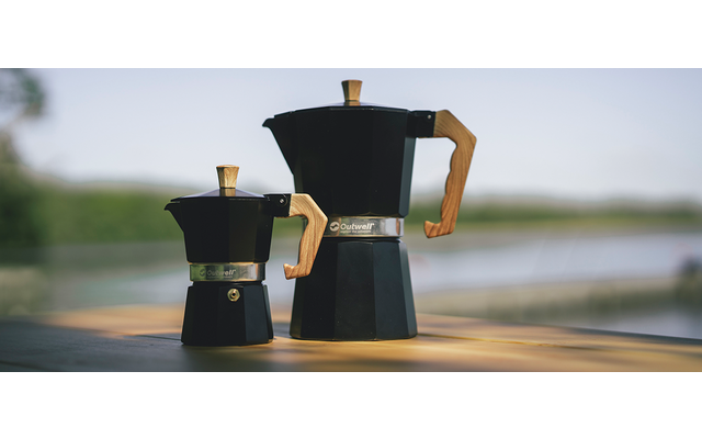 Twee zwarte espressomachines op een houten plank met een wazige achtergrond van water en bomen