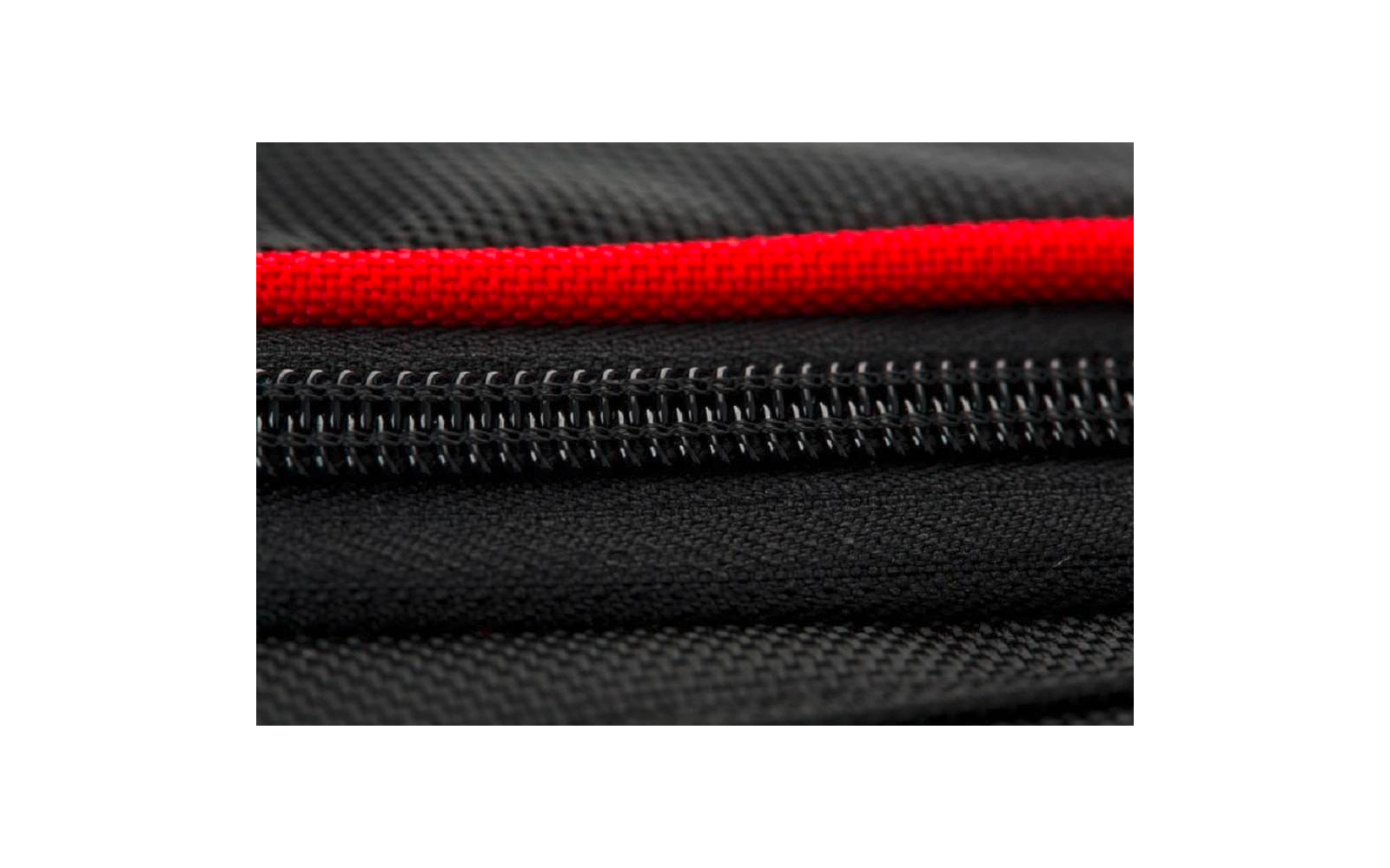 Gros plan d'une fermeture éclair noire sur un tissu noir avec un bord de tissu rouge