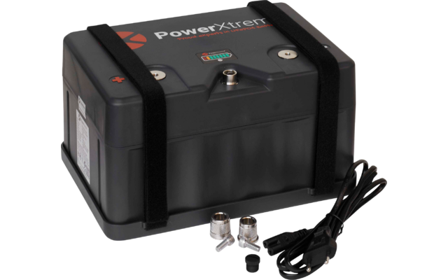 Schwarzes rechteckiges Gerät mit Aufschrift PowerXtreme, zwei schwarzen Klettbändern, zwei Metallanschlüssen oben, davor Kabel mit Stecker, zwei Metallverschraubungen und eine kleine schwarze Abdeckung