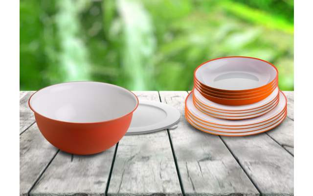 Meerdere witte borden en een oranje-witte kom op een houten tafel met een groene achtergrond