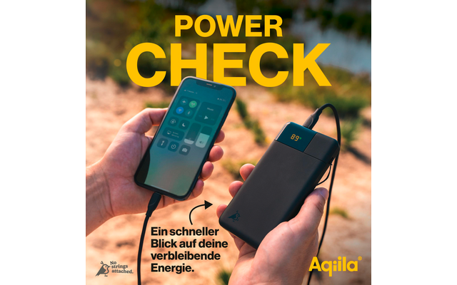 Main tenant un smartphone à côté d'un appareil noir avec écran et câble de connexion sur fond flou